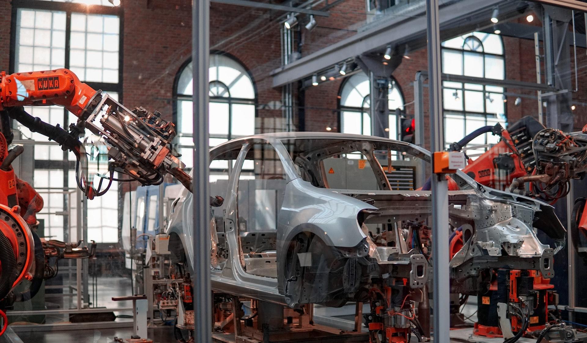 gray vehicle being fixed inside factory using robot machines